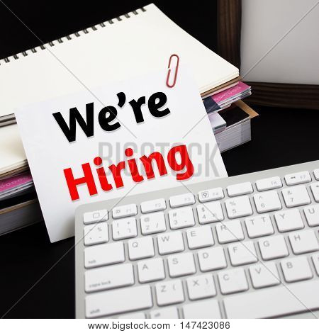 Word text We're hiring on white paper card / business concept
