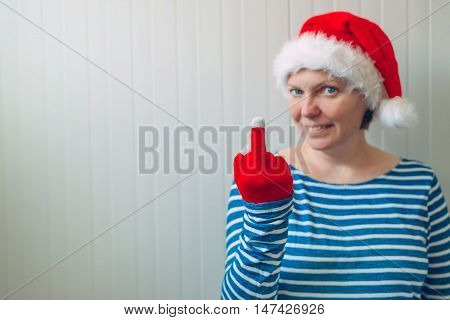 Woman with Christmas Santa Claus hat giving middle finger rude gesture of serious and angry person selective focus