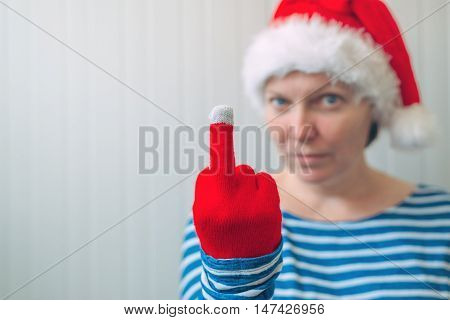 Woman with Christmas Santa Claus hat giving middle finger rude gesture of serious and angry person selective focus