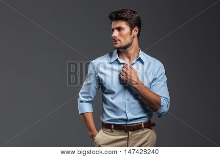 Portrait of a casualman buttoning his shirt isolated on a gray background