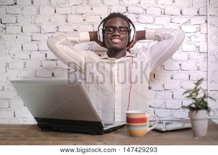Relaxed man listening to music while sitting at his desk