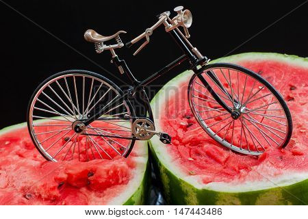 Paradox. Vintage bicycle standing on top of a large cut in half scarlet ripe watermelon