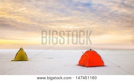 Bright tents camping of the expedition on the ice of the Northern territory. Wild adventure tours and trekking in the harsh winters of Northern nature. Courage and fortitude of traveler. North pole.