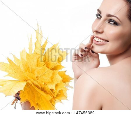 closeup portrait of attractive  caucasian smiling woman brunette isolated on white studio shot lips toothy smile face hair  looking at camera tooth hand holding yellow marple autumn leaves