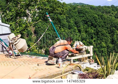 Sochi, Russia - MAY 22, 2016: Mason worker tiler making floor in a new buildings of the SKYPARK AJ Hackett Sochi, in the Sochi National Park, a scenic location Ahshtyrskaya gorge