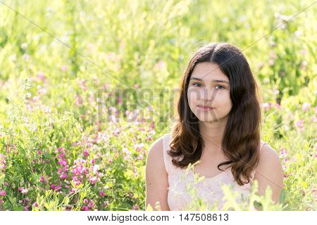 Modest well-groomed girl on the summer flower meadow