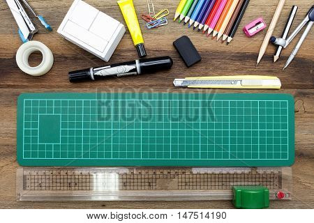 Business concept:stapler,glue,scissor,cutter,tape,pen,pencil,clip,ruler,rubber, cutting mat,divider,sharpener,wooden block calendar and color pencil on wooden