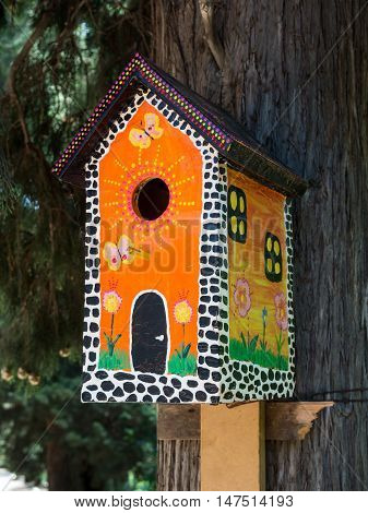 Bright painted under the multi-storey house birdhouse on a tree trunk