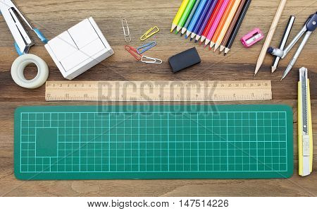 Business concept:stapler,glue,scissor,cutter,tape,pen,pencil,clip,ruler,rubber, cutting mat,divider,sharpener,wooden block calendar and color pencil on wooden