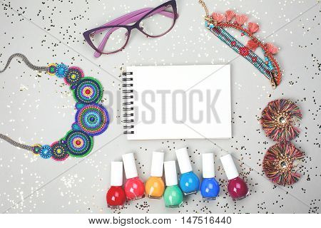 Beautiful multicolored frame made of woman accessories and rainbow of nail polishes. All stuff is lying on grey festive background. Place for your text.