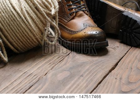 Men's shoes hank jute rope on the background of wooden planks with space for text