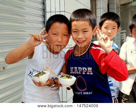 Wan Jia China - June 12 2007: A group of little Chinese boys eating their lunch from small rice bowls in front of their school