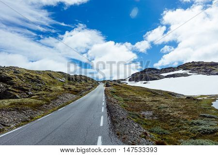 Asphalt road in Norway with snowy mountains in the background