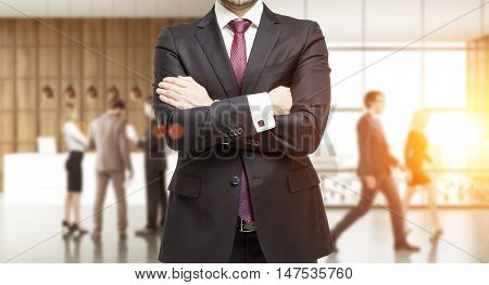 Torso of businessman in suit standing in busy office of consulting company. Concept of charismatic leader. Toned image