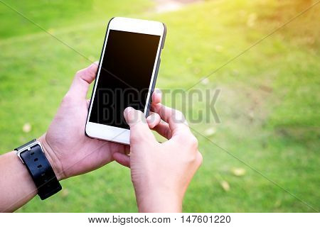 Hand Using Mobile phone with blank screen in the park Vintage Tone