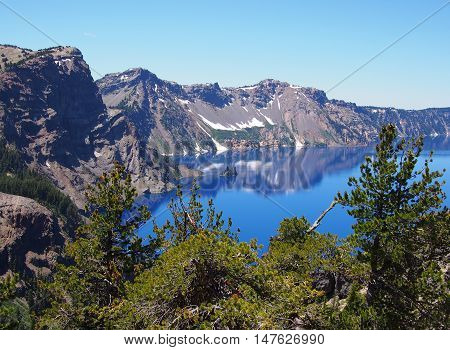 Jagged Crater Lake Rim reflects in the beautiful blue lake.