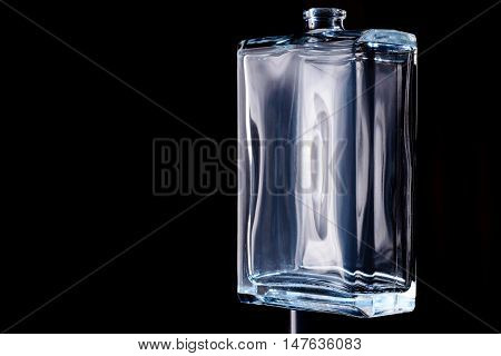 Rectangular transparent bottle of cologne isolated on a black background.