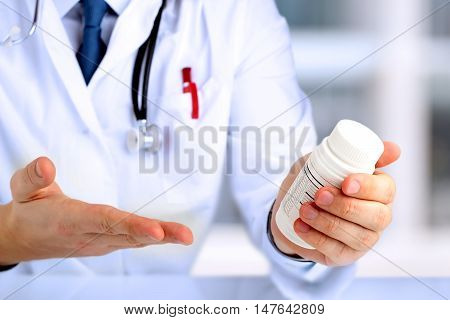 Cropped image of doctor showing a bottle of pills to the patient
