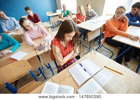 education, bullying, conflict, problem and people concept - students gossiping behind classmate back at school
