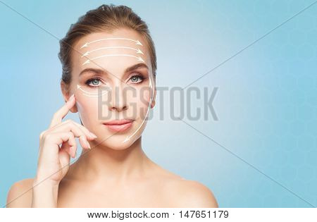 beauty, people , plastic surgery and anti-age concept - beautiful young woman showing her cheekbone over blue background