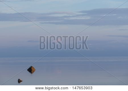 Evening sunlight on coast pink clouds blue sky reflection on water. Beach in summer. Seaside natural environment. Shore in Osmussaar Island Nature Reserve in Estonia National Park in Europe