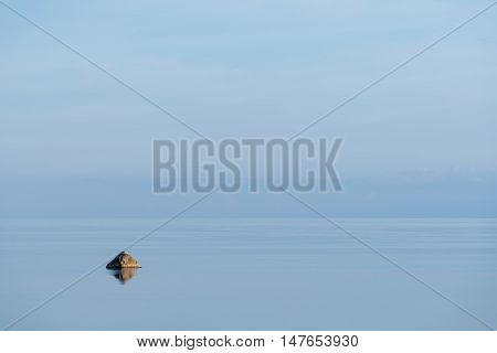 Evening sunlight on the coast blue sky reflection on the water. Beach in summer. Seaside natural environment background. Shore in Osmussaar Island Nature Reserve in Estonia National Park in Europe