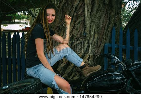 girl on a motorcycle in the shade of a tree. vintage