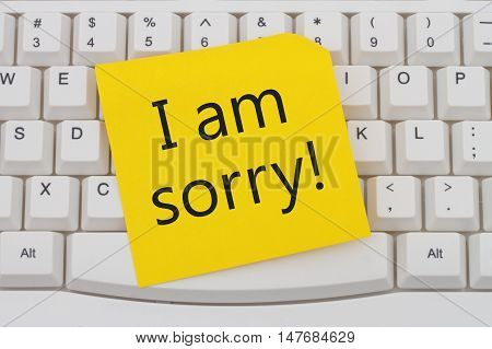 A close-up of a keyboard with yellow sticky note with text I am Sorry