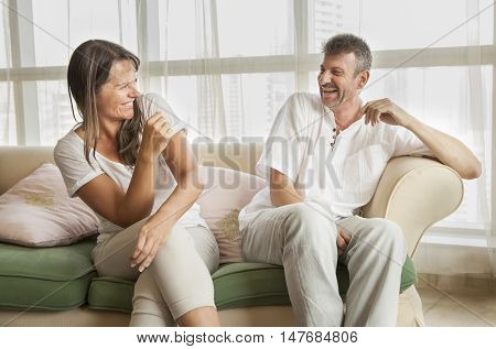 middle aged couple laughing at home on a sofa