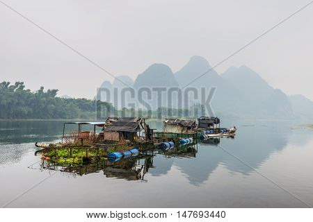 Yangshuo China - October 21 2013: Houses and bamboo raft on the Li river floating island in the overcast nasty day in rural Yangshuo China.