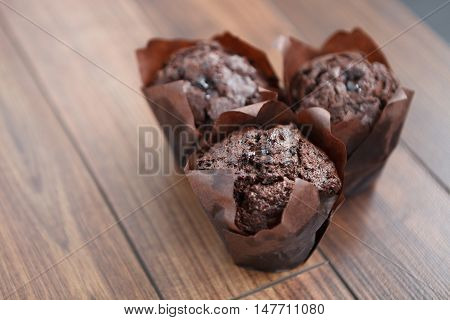 Three Delicious Chocolate Muffins On Wooden Table