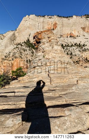 Shadow of Woman with bagpack up on the mountain taking pictire of the rock Summit of Angel's Landing Zion National Park Utah