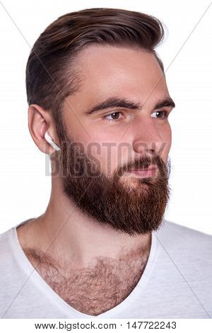 Young bearded man with wireless earphones on his ears. studio shot isolated on white background.