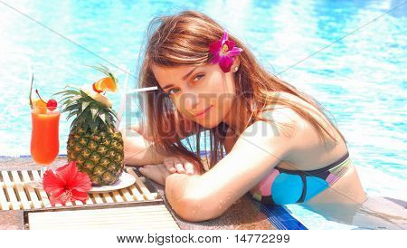 Meisje in het tropische zwembad met cocktail