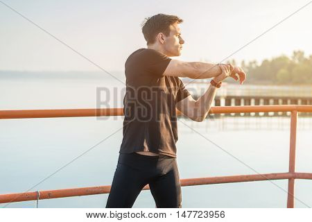 Jogger warming up exercising, stretching arms and shoulder. Fitness, sport on fresh air