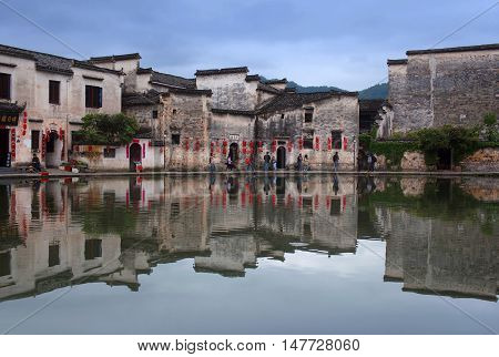 HONGCUN, CHINA - APRIL 20, 2014: Tourist walking around Moon Lake in historical Hongcun Village in Anhui Province.