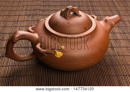 brown Chinese teapot of Yixing clay with traditional ornament on bamboo Mat