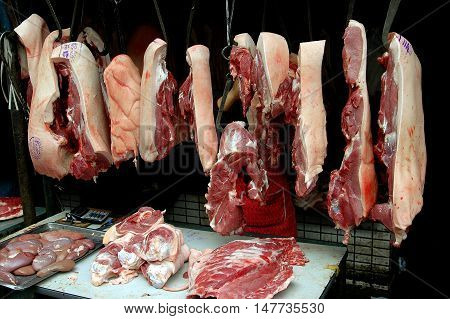 Chengdu China - April 23 2005: Slabs of fresh pork hang from iron meat hooks at the Qing Shi Qiao outdoor market hall