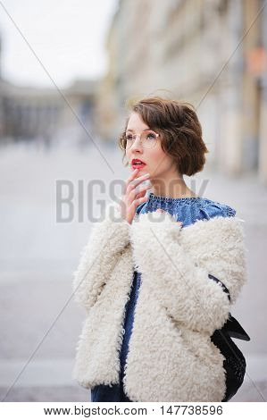 A street portrait of a beautiful modern girl looking up in astonishment through his glasses.