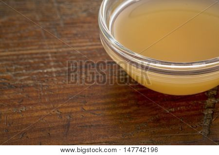 unfiltered, raw apple cider vinegar with mother  - a small glass bowl against rustic wood with a copy space