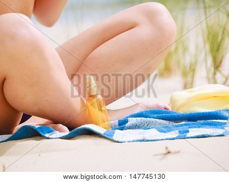 Skin protection in summer. Woman on beach using sun oil. Young beauty girl taking sunbath on sunny day. Holidays time.