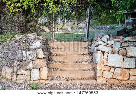 Old set of steps with rock retaining wall and fence with vine