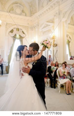 Beauty bride and handsome groom are registering the marriage. Wedding couple is marrying. Beautiful model girl in white dress and in lace veil. Man in suit. Female and male portrait. Cute lady and guy