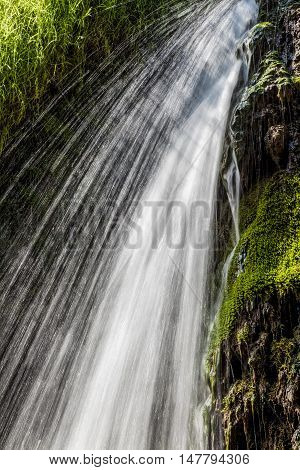 Movement blurred water falling over the moss of a waterfall. Vertical image.