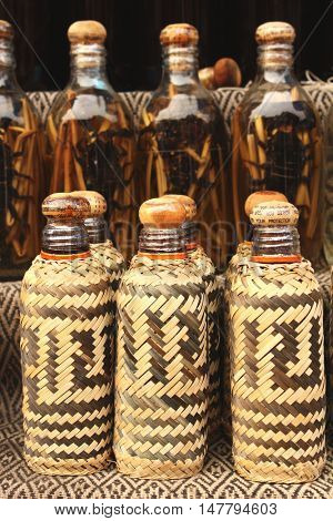 Bottles in a cane bamboo cover with traditional laotian alcohol with scorpion, Xang Hai village, Luang Prabang province, Laos