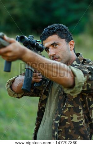Man of Arab nationality in camouflage with a gun for trap shooting aiming at a target