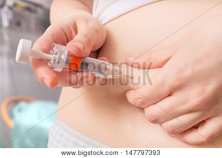 Blood thinners concept. Woman is injecting heparin injection to belly with syringe.