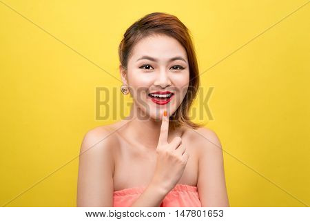 Cheerful beautiful asian young woman with charming smile over yellow background. Beauty fashion. Cosmetics.