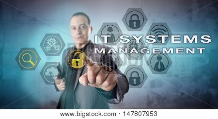 Experienced network administrator is activating IT SYSTEMS MANAGEMENT onscreen. Kind yet tense and concentrated facial expression. Information technology concept for computer systems administration.