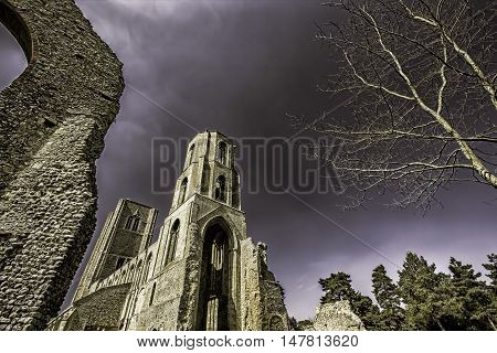 This is a picture of the partly ruined Wymondham Abbey a magnificent Norman church in Norfolk UK. It was established in 1107. The tone emphasises the dramatic nature of the building as does the perspective which also allows some central copy space.